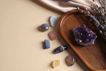 Different beautiful gemstones and lavender flowers on beige background, flat lay. Space for text