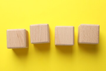 Blank wooden cubes on yellow background, flat lay