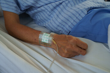 Focus on the wrist of an elderly patient with an IV line.	