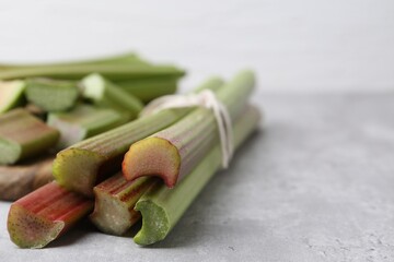 Fresh rhubarb stalks on grey table, closeup. Space for text