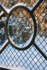 Ein Gartenzaun mit Schnee, dahinter eine Winterlandschaft.