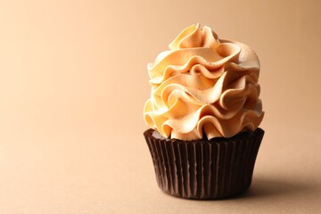 Delicious cupcake with colorful cream on beige background, closeup. Space for text
