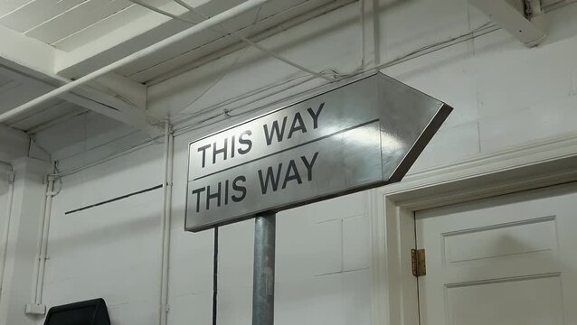 Wayfinding placard featuring directional indicator inscribed with the words THIS WAY