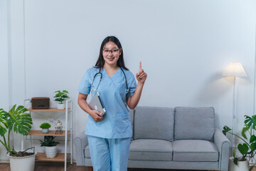 Smiling medical professional in blue scrubs with stethoscope shows finger up in modern clinic room...