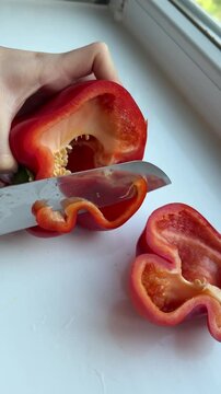 Hands open red bell pepper into two halves close-up top view. High quality 4k footage