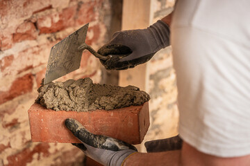 Maurer streicht Zement auf einem Ziegel auf