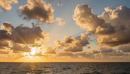 Serene sunset over the ocean with fluffy clouds and golden rays  
