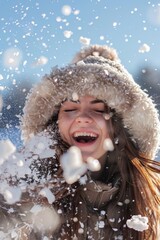 Young woman joyfully playing in the snow wearing a warm hat and scarf during a bright winter day in a snowy landscape