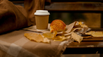 Autumn coffee break with croissant and fall leaves