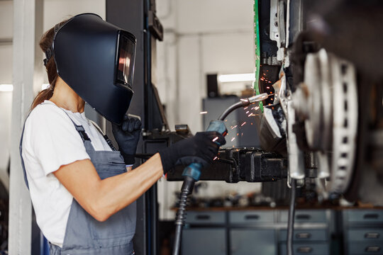 A skilled female welder is actively performing precise metal work in a wellequipped professional workshop setting