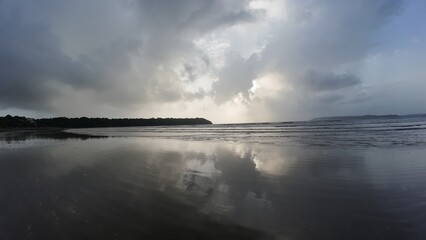 Serene Coastal Sunset with Cloud Reflections on Wet Sand Beach