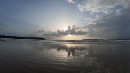 Tranquil Coastal Scenery: Rhythmic Movement of the Water and Symmetrical Reflections During the Golden Hour on a Broad, Flat Beach.