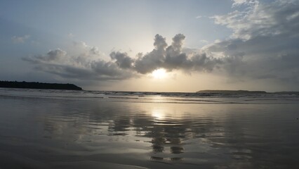 Tranquil Coastal Scenery: Rhythmic Movement of the Water and Symmetrical Reflections During the Golden Hour on a Broad, Flat Beach.