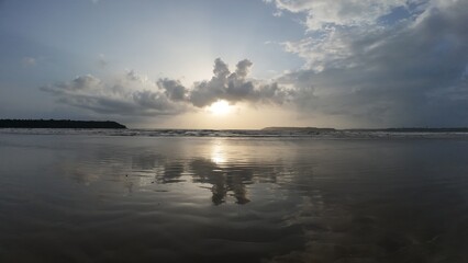 Obraz premium Tranquil Coastal Scenery: Rhythmic Movement of the Water and Symmetrical Reflections During the Golden Hour on a Broad, Flat Beach.