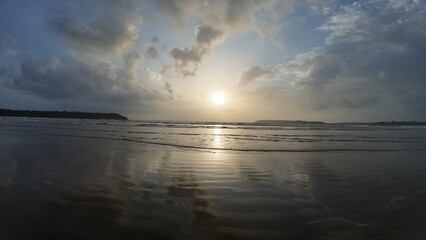 Idyllic Coastal Sunrise with Gentle Waves, Dramatic Clouds, and Mirror-Like Reflections