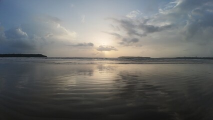 A Tranquil and Moody Seascape Capturing the Vibrant Light of Sunrise or Sunset Reflected Symmetrically on Wet Sand and Water.