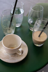 Empty coffee cup and used glasses on table. Concept of consumption, routine, leisure, social interaction, everyday life, urban cafe culture, simple lifestyle, human habit. Vertical photo