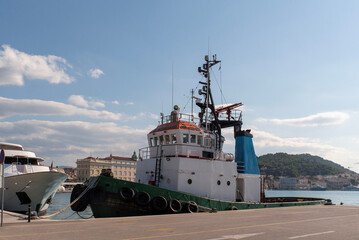 Harbor tugboat at quay with wheelhouse and fendered bow © Sergey