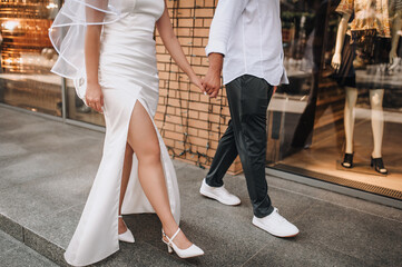 Young bride and groom, happy newlyweds walking down the street of a European city holding hands. Wedding photography.