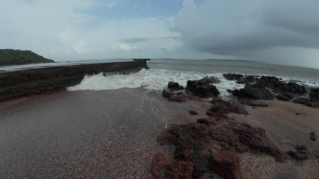 Powerful ocean waves crashing against rugged coastal rocks under a stormy sky