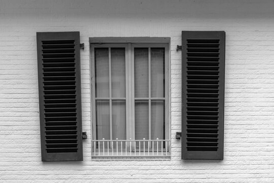 Shuttered window on a white brick wall with green shutters, highlighting architectural details in simple design - Powered by Adobe