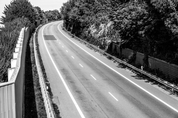 Curved road surrounded by greenery on a clear day near a quiet area perfect for a peaceful drive