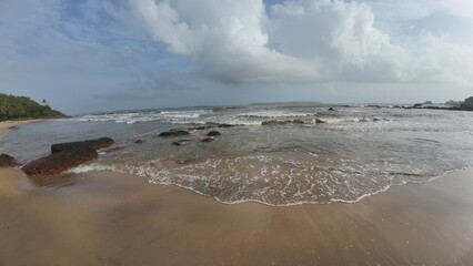 The Turbulent Power of the Sea: Wide Angle View of the Churning Waves and White Surf Washing Over Rugged Shoreline Rocks and Sandy Beach
