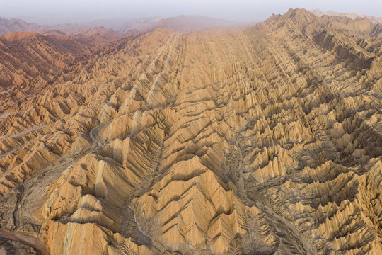 Aerial view of rugged badlands stretch, etched by time and weather, creating a tapestry of earthy tones and stark shadows, a geological masterpiece, &Atilde;&oelig;r&Atilde;&frac14;mqi, Xinjiang, China.