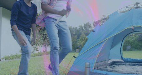With son holding stake, father hammering stakes assembling dome tent for camping - Powered by Adobe