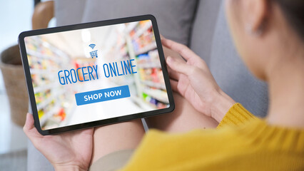 Hand using digital tablet  with grocery online shopping over blur supermarket on screen background, business and technology, lifestyle concept