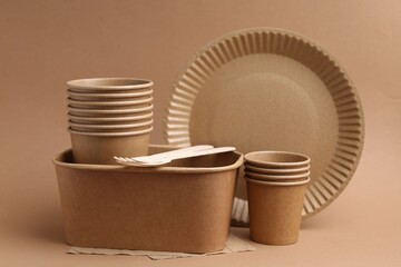 Set of disposable tableware on brown background, closeup