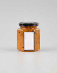 A jar of passion fruit and mango jam on a gray background. Blank label