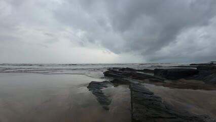 Moody and tranquil landscape of an evening beach, with a rocky shore and calm, misty ocean.