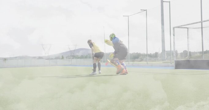 Attacker stepping dribbling orange ball around diving goalkeeper toward goal for hockey training