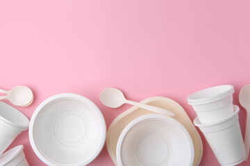 Set of disposable plastic tableware on pink background, flat lay. Space for text