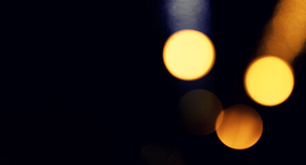 Bokeh lights at night. Large golden blurred circles glowing with brilliance and shimmer on dark