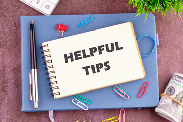 Helpful Tips words in a notebook in a composition with office supplies, top view