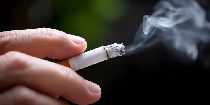 喫煙タバコを持つ手 黒色の背景に煙が漂う