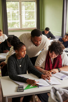 High angle view of male teacher helping students in solving math equation at junior high classroom