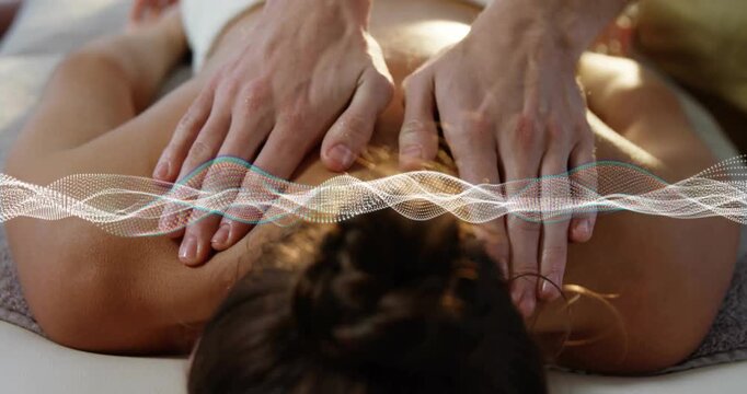 Therapist pressing on client's back kneading while digital wave syncing for spa relaxation