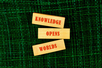 Education,student,university concept. KNOWLEDGE OPENS WORLDS made of wooden blocks on fabric background, top view