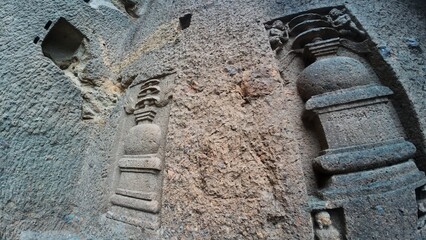 The Rich Texture and Fine Craftsmanship of Ancient Rock-Cut Reliefs Adorning a Wall in the Kanheri Cave Complex, Evoking Spiritual Heritage.