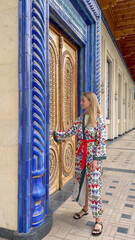 Woman in Uzbek traditional attire walking near memorial architecture in Tashkent