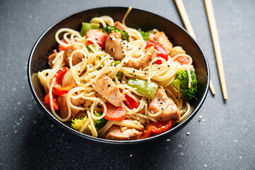 Stir fry chicken with vegetables and noodles at black background.