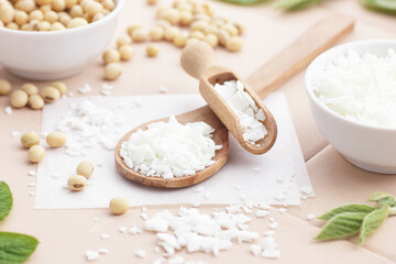 Soy wax with soybeans and fresh plant leaves on natural background, soy candles making and natural cosmetic ingredient  concept