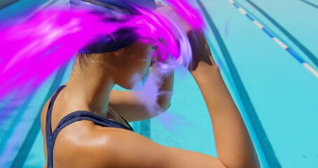 Female swimmer harnessing purple energy swirl initiating fitting blue cap and goggles for sports