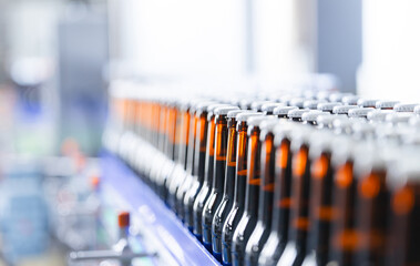 Modern beer factory bottling line with rows of bottles in production process