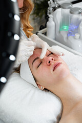 Naklejka premium Young woman receiving hydra facial treatment for exfoliation, rejuvenation and hydration of her face skin. Modern facial hydro micro dermal abrasion peeling beauty procedure. Hydra vacuum cleaner.