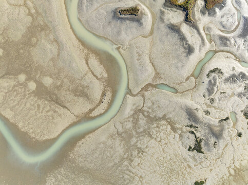 Aerial view of winding turquoise channels cut through the textured, sun-baked earth, creating a stark yet beautiful contrast of colors and patterns, Bay of C&Atilde;&iexcl;diz, C&Atilde;&iexcl;diz province, Andalusia, Spain.