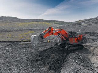 Aerial view Excavator in open pit coal mine under cloudy sky, industry landscape from drone